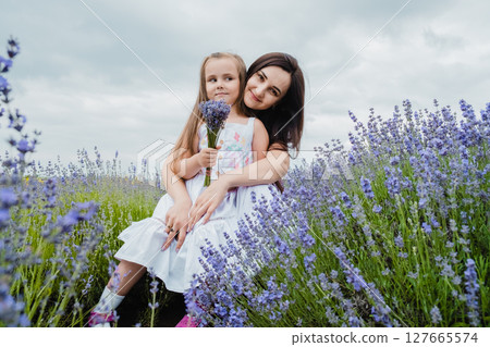 The mother gently embraces her daughter against the backdrop of the lavender field The mother gently embraces her daughter against the backdrop of the lavender field 127665574
