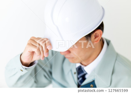 A middle-aged male businessman wearing green work clothes and holding a helmet A middle-aged male businessman wearing green work clothes and holding a helmet 127665599
