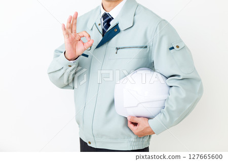 身穿綠色工作服、手持頭盔、做圓形標誌的中年男性商人 127665600