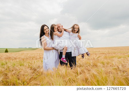 The family poses in front of a golden barley field 127665720