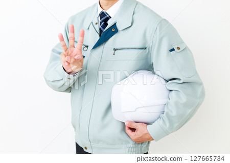一位身穿綠色工作服的中年男性商人,手持頭盔,三根手指向上指 一位身穿綠色工作服的中年男性商人,手持頭盔,三根手指向上指 127665784