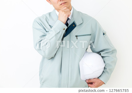 A worried middle-aged male businessman wearing green work clothes 127665785