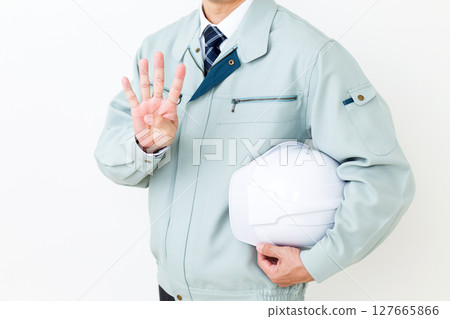一位身穿綠色工作服的中年男性商人，手拿頭盔，四指向上 127665866