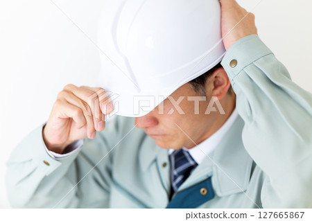 一位身穿綠色工作服、戴著頭盔的中年男性商人 127665867