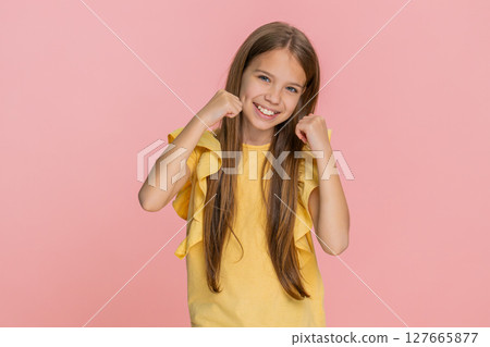 Child girl kid showing victory win gesture while happily and joyfully celebrating success with smile 127665877