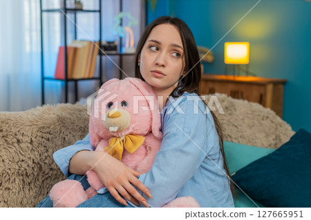 Woman on sofa hugging plush bunny feeling lonely romantic missing beloved tenderness, divorce 127665951