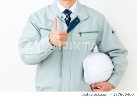 一位身穿綠色工作服、手持安全帽、豎起大拇指的中年男性商人 127666460
