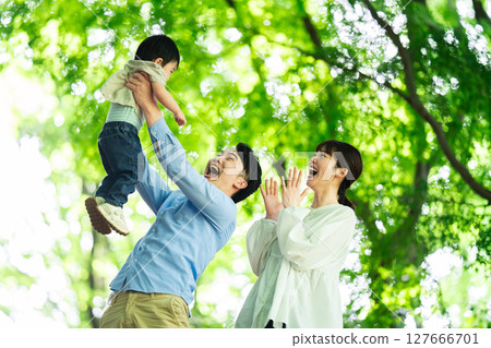 A father playing with his one-year-old son under the fresh greenery 127666701