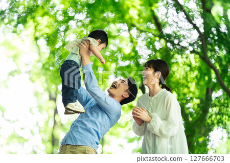 A father playing with his one-year-old son under the fresh greenery 127666703