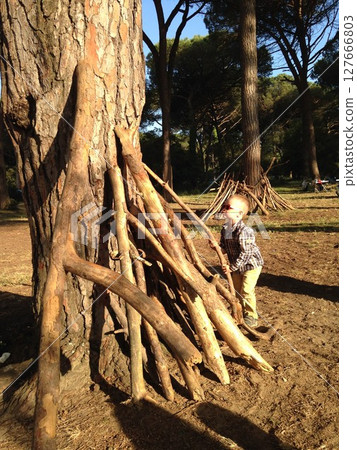 Child Building Stick Shelter in Forest Setting 127666803
