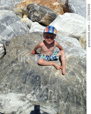 Child Sitting on Rocks in Swimwear on a Sunny Day 127666806