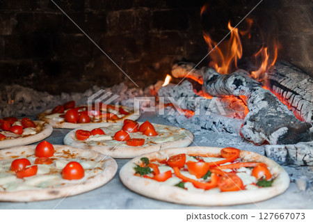 Wood-Fired Pizza Baking in Brick Oven with Flames. Rustic Italian Cuisine, Fresh Tomatoes, Molten Cheese, Close-Up Food Photography Wood-Fired Pizza Baking in Brick Oven with Flames. Rustic Italian Cuisine, Fresh Tomatoes, Molten Cheese, Close-Up Food Photography 127667073