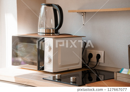 Minimalist Kitchen Counter Setup with White Microwave, Electric Kettle, and Outlets, Light Gray Walls, Modern Home Appliance Scene 127667077