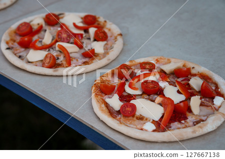 Two Homemade Margherita Pizzas on a Gray Table Outdoors, Red Tomatoes, Mozzarella, Freshly Baked, Summer Food Photography, Rustic Style Two Homemade Margherita Pizzas on a Gray Table Outdoors, Red Tomatoes, Mozzarella, Freshly Baked, Summer Food Photography, Rustic Style 127667138