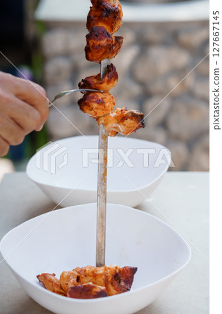 Delicious Grilled Chicken Souvlaki Skewer with Golden-Brown Meat Served with White Bowls on Stone Table, Appetizing Food Photography 127667145