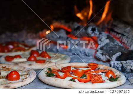 Wood-Fired Pizza Baking in Traditional Oven with Cherry Tomatoes and Basil, Rustic Italian Cuisine, Warm Flames, Food Photography Wood-Fired Pizza Baking in Traditional Oven with Cherry Tomatoes and Basil, Rustic Italian Cuisine, Warm Flames, Food Photography 127667155