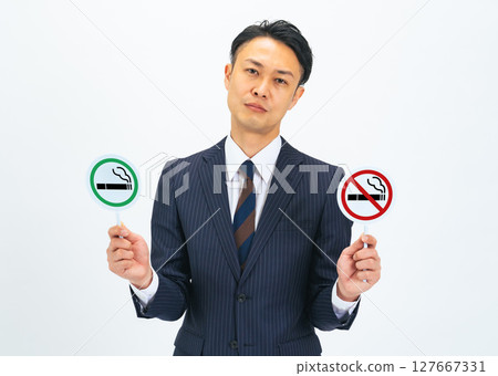 A middle-aged male business person holding a smoking sign and a no smoking sign A middle-aged male business person holding a smoking sign and a no smoking sign 127667331
