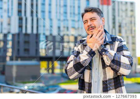 Mature Caucasian businessman feeling toothache bad unpleasant symptoms suffering from pain outdoors Mature Caucasian businessman feeling toothache bad unpleasant symptoms suffering from pain outdoors 127667393