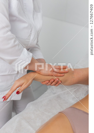 Cosmetologist massagist making woman treatment massage scrubbing hand with scrub in spa clinic 127667409