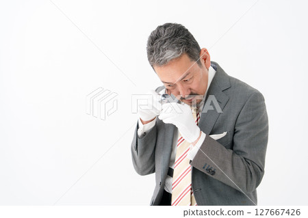 A man examining something with a magnifying glass A man examining something with a magnifying glass 127667426