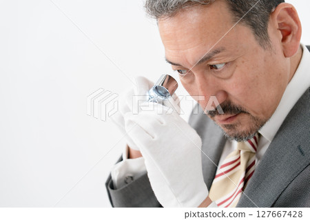 一名男子用放大鏡進行評估 127667428