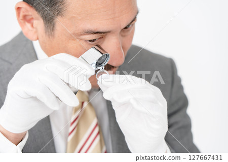 A man examining something with a magnifying glass 127667431