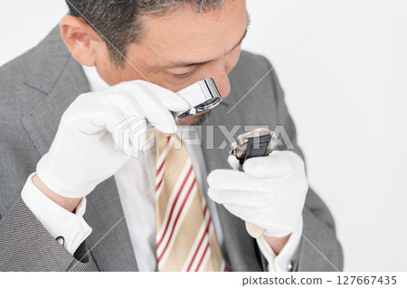 A man examining something with a magnifying glass A man examining something with a magnifying glass 127667435