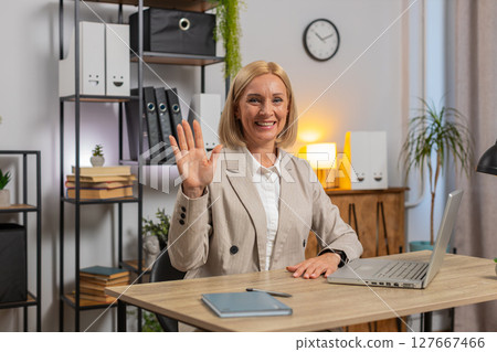 Portrait of mature businesswoman in suit looking at camera after using laptop at home office desk 127667466