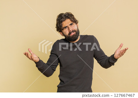 Confused man raising hands asking reason of failure demonstrating disbelief on beige background Confused man raising hands asking reason of failure demonstrating disbelief on beige background 127667467