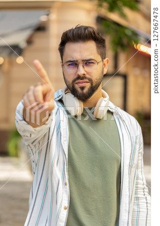 Upset Caucasian man reacting to unpleasant awful idea shaking finger at camera on city urban street 127667478