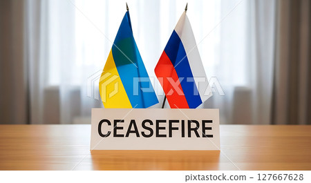 Ukraine and Russia flags stand side by side on a table, with a prominent sign labeled "CEASEFIRE" in bold letters, symbolizing peace or negotiation between the two nations 127667628