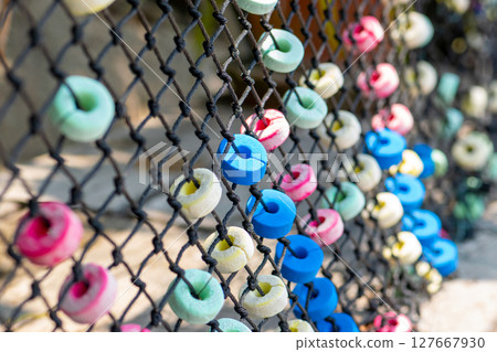 Colorful and round soft decorations on the net fence Colorful and round soft decorations on the net fence 127667930