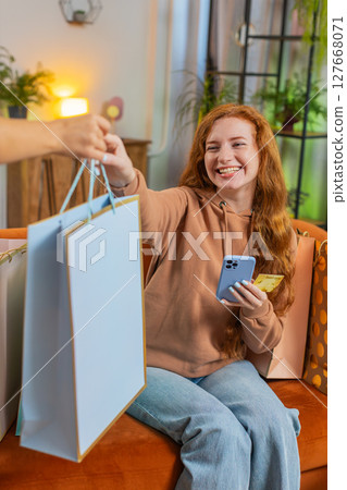 Excited young Caucasian woman with shopping bags receiving order sitting on sofa couch at home Excited young Caucasian woman with shopping bags receiving order sitting on sofa couch at home 127668071