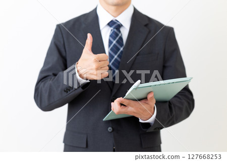 一位身著西裝的中年男性商人拿著活頁夾豎起大拇指 一位身著西裝的中年男性商人拿著活頁夾豎起大拇指 127668253