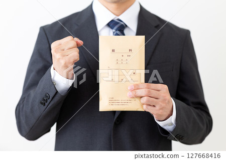 A middle-aged male businessman in a suit making a fist pump while holding a pay envelope 127668416