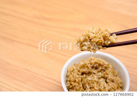 Brown rice in a bowl on a wooden table background Brown rice in a bowl on a wooden table background 127668902