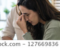 Supportive couple in emotional moment at home as woman struggles with sadness and stress, expressing 127669836