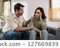 Supportive couple in emotional moment at home as woman struggles with sadness and stress, expressing 127669839