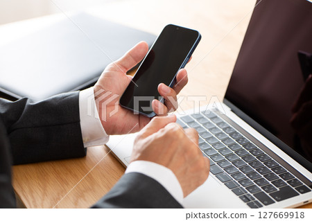 A middle-aged male businessman in a suit working on a computer at a desk 127669918