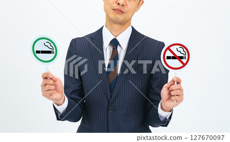 A middle-aged male business person holding a smoking sign and a no smoking sign 127670097