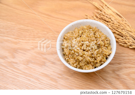 木桌背景上碗裡的糙米和米穗 木桌背景上碗裡的糙米和米穗 127670158