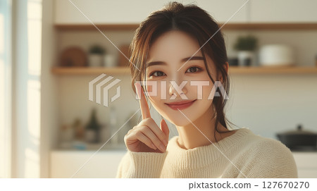 Smiling Korean woman shows a lightbulb moment in a cozy kitchen setting during daytime 127670270