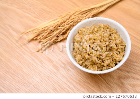 木桌背景上碗裡的糙米和米穗 127670638