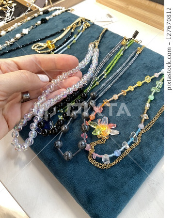 Glass bead necklaces displayed on teal velvet background showcasing handcrafted jewelry design Glass bead necklaces displayed on teal velvet background showcasing handcrafted jewelry design 127670812