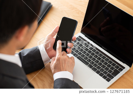 一位身穿西裝的中年男性商人在辦公桌前使用電腦工作 127671185