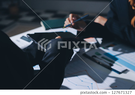 Group of business women working on a financial data expenses document. Group of business women working on a financial data expenses document. 127671327