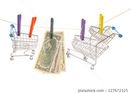 Two miniature shopping carts hung on a clothesline with colorful clothespins 127672325