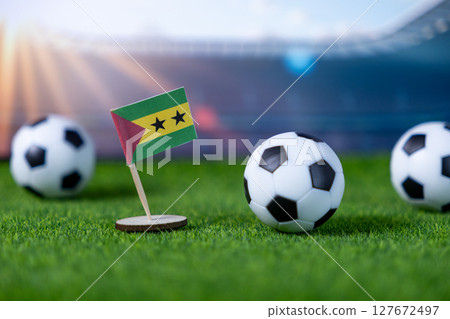 Sao Tome and Principe flag stands on a vibrant green football pitch with balls, symbolizing national pride and international sports event Sao Tome and Principe flag stands on a vibrant green football pitch with balls, symbolizing national pride and international sports event 127672497