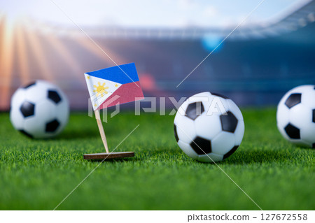 Miniature Philippines flag and soccer balls on green stadium grass, symbolizing international football championships, national team pride, and sports events 127672558