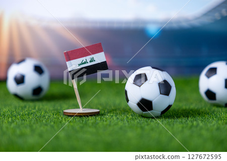 A small Iraqi flag on artificial grass with soccer balls, depicting national sporting pride for football events and tournaments A small Iraqi flag on artificial grass with soccer balls, depicting national sporting pride for football events and tournaments 127672595